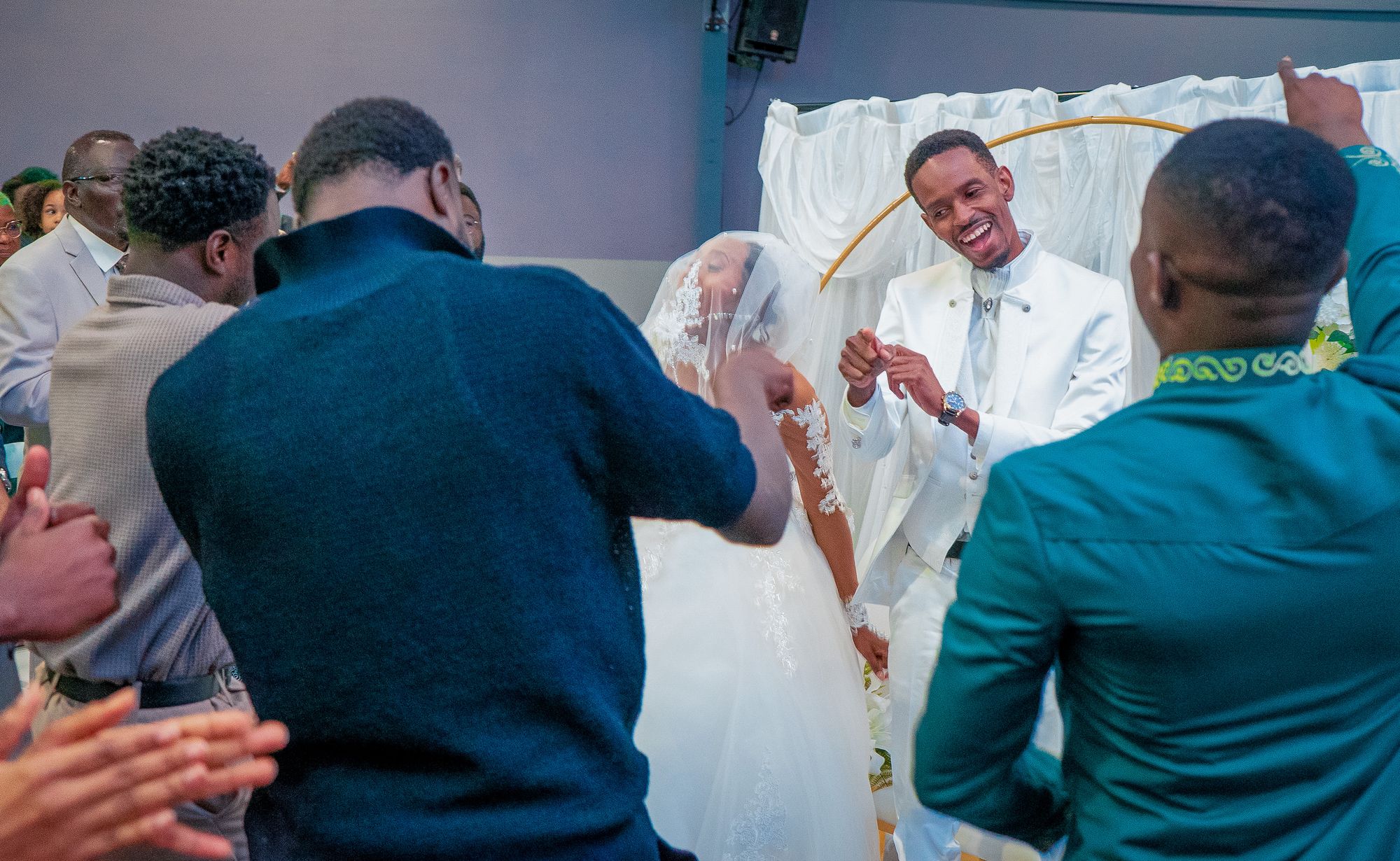 Les mariés rient entourés de leurs invités qui dansent pendant la cérémonie